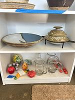 Shelf view showing platter, casserole on stand, decanter, mugs, stone fruit