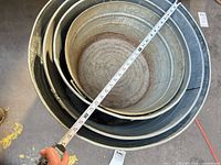 Nested set of four galvanized steel tubs with tape measure showing roughly 32 in diameter
