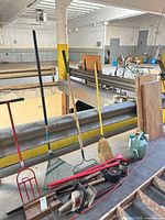 Overall lot showing long-handled tools, broom, jug, spray cans, wood pieces