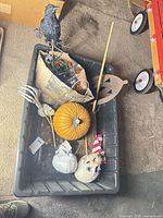 Contents in tote: faux pumpkin, crow on stake, bag with lights, metal jack-o-lantern stake, broom, skulls, skeleton hand