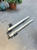 Two aluminum rails with carriage assemblies on floor