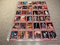 Fronts of Battlestar Galactica trading cards arranged in rows showing artwork and red borders