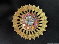 Top view of gold-tone sunburst brooch showing rhinestone arrangement