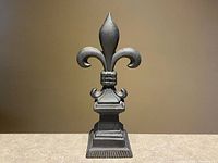 Front view of cast iron fleur-de-lis sculpture showing full form and base