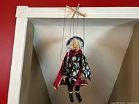 Full view of hanging marionette showing costume, face, wand, and control bar