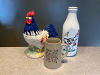 All three items grouped: stoneware syrup jug, ceramic milk bottle, ceramic rooster jar