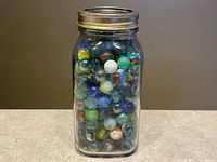 Front view of clear Mason jar filled with colourful marbles