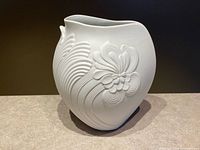 front view of white bisque porcelain vase showing floral relief