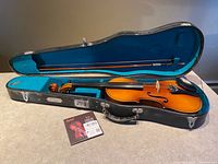 Violin, bow, case with blue interior, sealed string set displayed