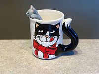 Front view of cat face mug with mouse figure and tail handle