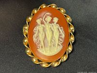 Front view of cameo brooch showing Three Graces relief and gold-tone frame