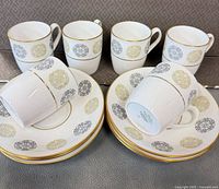 Six cups and six saucers arranged, showing pattern and gold rim