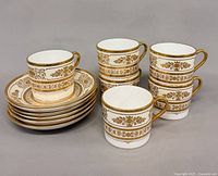 Six cups stacked beside six saucers displaying Argyle pattern and gilt detailing