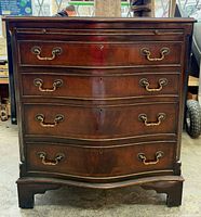 Front view of mahogany bow front chest showing four drawers and brass pulls