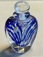Perfume bottle front view showing blue ribbon design and stopper in place