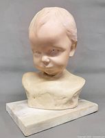 Front view of ceramic baby bust on marble base