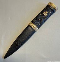 Full view of letter opener in sheath showing overall design