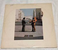 Front of album jacket showing handshake with man on fire image