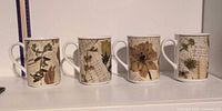 Front view of four mugs lined up showing full pattern