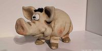 front angled view of ceramic piggy bank showing eyes, snout and hooves