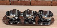 Front angled view of set showing mirror finish and three bowls on tray
