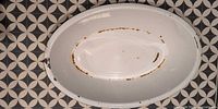 Top view of oval enamel basin showing interior wear and rust