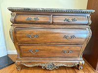 Front view of bombe-style dresser showing four drawers, carved details and hardware