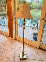Full view of brass-tone metal floor lamp with bell fabric shade