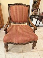 Front view of carved wood armchair showing upholstery and rope-twist trim