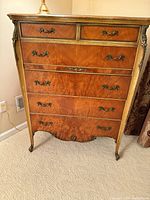 Front view showing six drawers, brass pulls, gilt trim