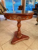 Full view of round pedestal side table showing carved apron, turned column and tripod base