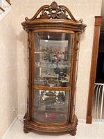 Full frontal view of bow-front curio cabinet showing overall design, glass panels, shelves, mirrored back