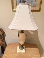 Full view of lamp on table showing stone base, metal fittings, shade and finial