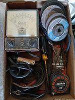 Top view of box showing Snap-on tester, abrasive discs, screwdriver, extractor pouch, tape measure, leads
