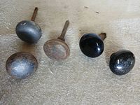 All four knobs laid out: two black porcelain, two rusted metal