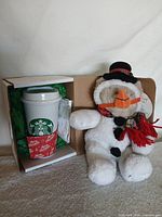 Travel cup and snowman plush side by side
