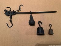 Full view of steelyard beam with attached pear weight and two separate hook weights on cardboard background