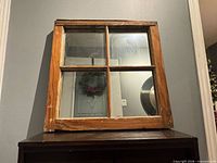 Front view of square wooden window frame with four mirrored panes