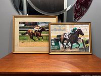 Both framed racehorse photographs on table