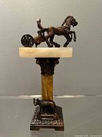 Front view of sculpture showing chariot, column, Capitoline Wolf base