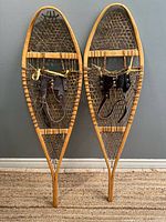 Full view of both wooden snowshoes standing side by side