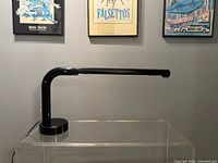 Side view of black Tube desk lamp on clear stand
