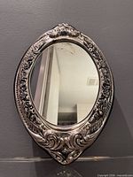 Front view of ornate oval silverplate mirror