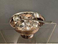 Punch bowl filled with cups and ladle resting on rim