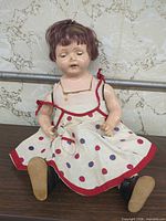 Full view of doll seated wearing polka dot dress and shoes