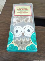 Front of retail package showing owl knit neck warmer