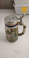 Full view of stein front showing football scene and pewter lid