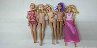 Five Barbie-size dolls lined up, showing clothing and hair variations