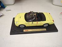 Left front perspective of yellow convertible model on display base