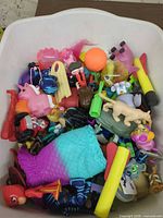 Top view of bin showing mixed figures, foam darts, mermaid tail, Peppa Pig